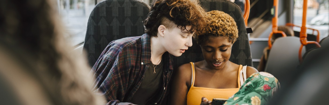 Young people looking at a phone on a bus